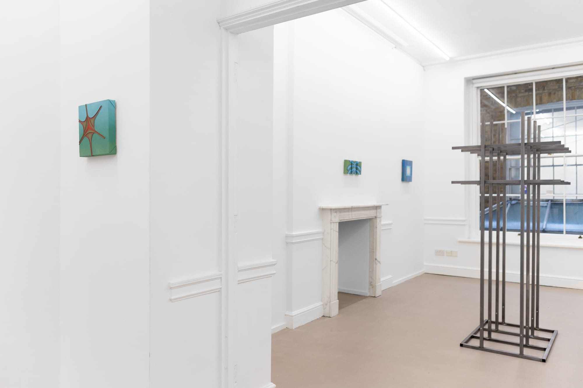 Installation view of a hallway with a teal painting and a steel grid sculpture by the window