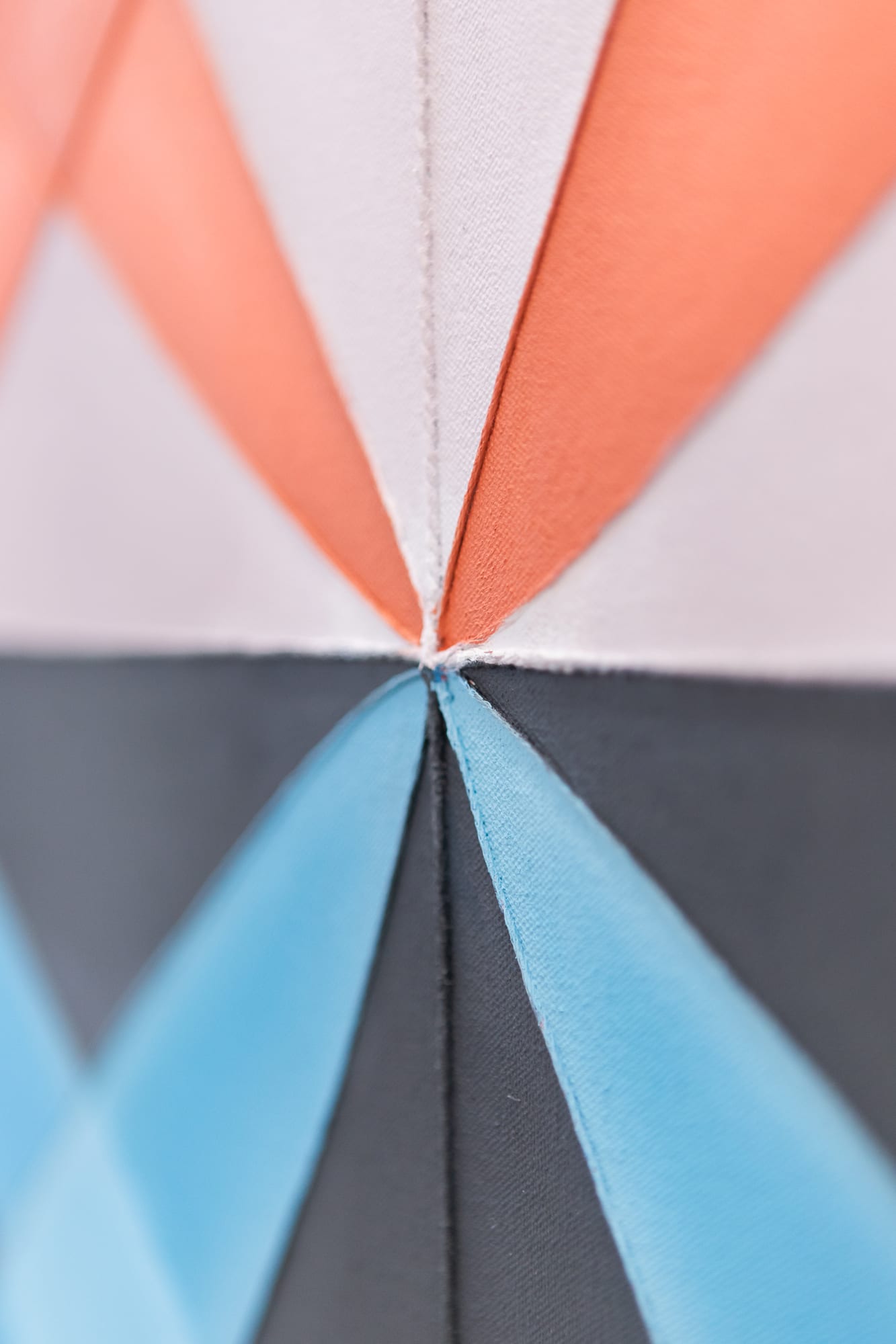 Macro detail of orange, blue, and grey triangular painted seams