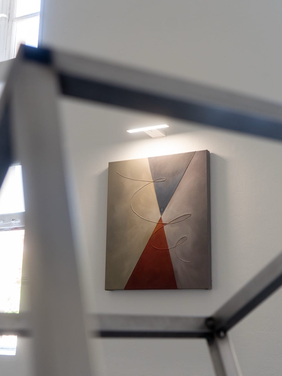 Geometric painting seen through the bars of a steel frame sculpture