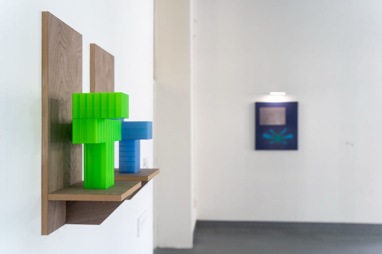 Bright green and blue 3D printed forms mounted on wooden shelves