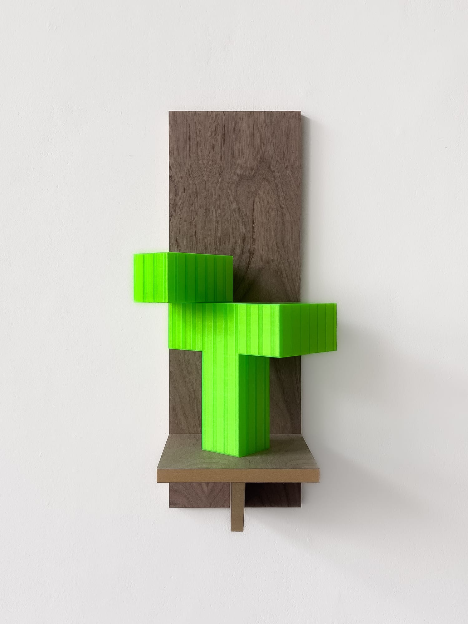 Bright green 3D-printed cross-form mounted on a wooden backing