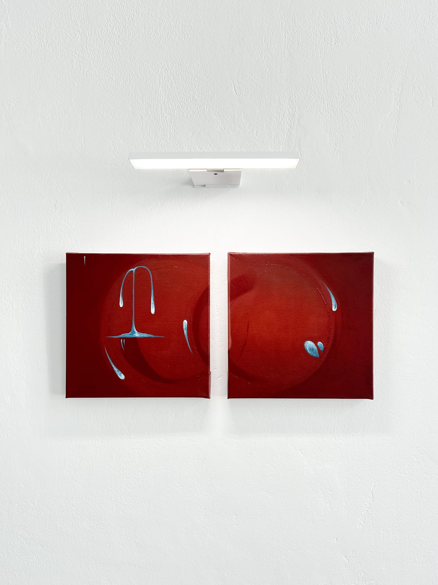 Red diptych beneath a gallery light